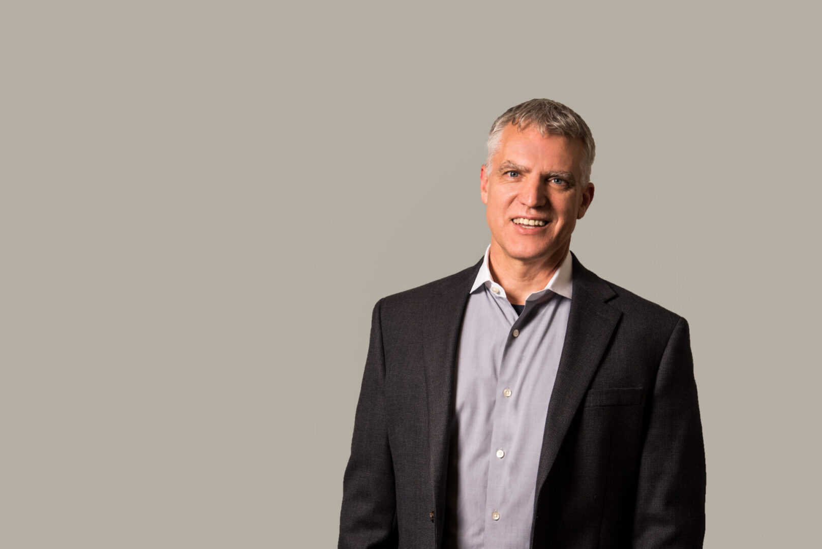 A picture of a gray-haired man wearing a button-up shirt with a black suit jacket